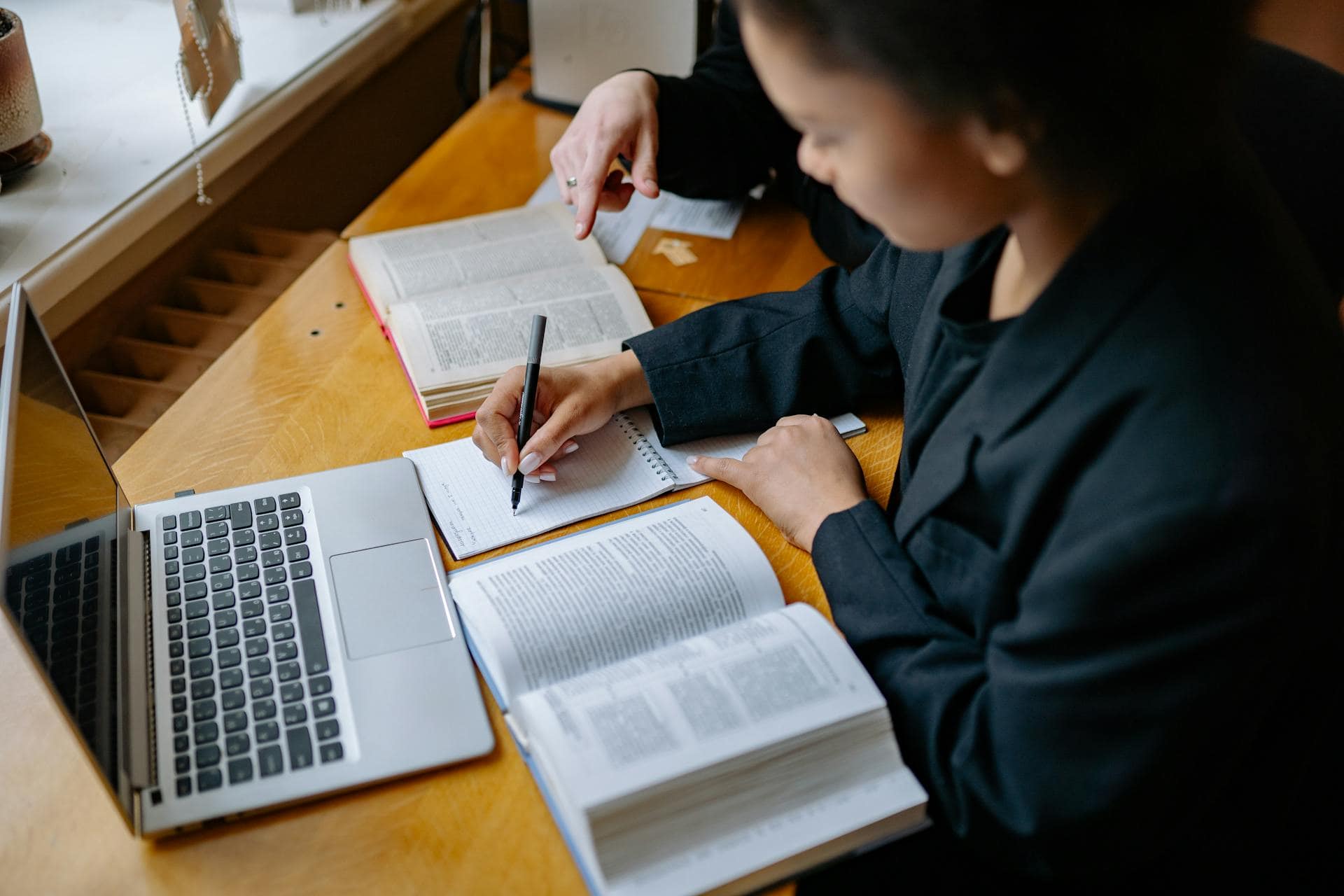 Estudiante practicando gramática en inglés desde casa con libros y ordenador.